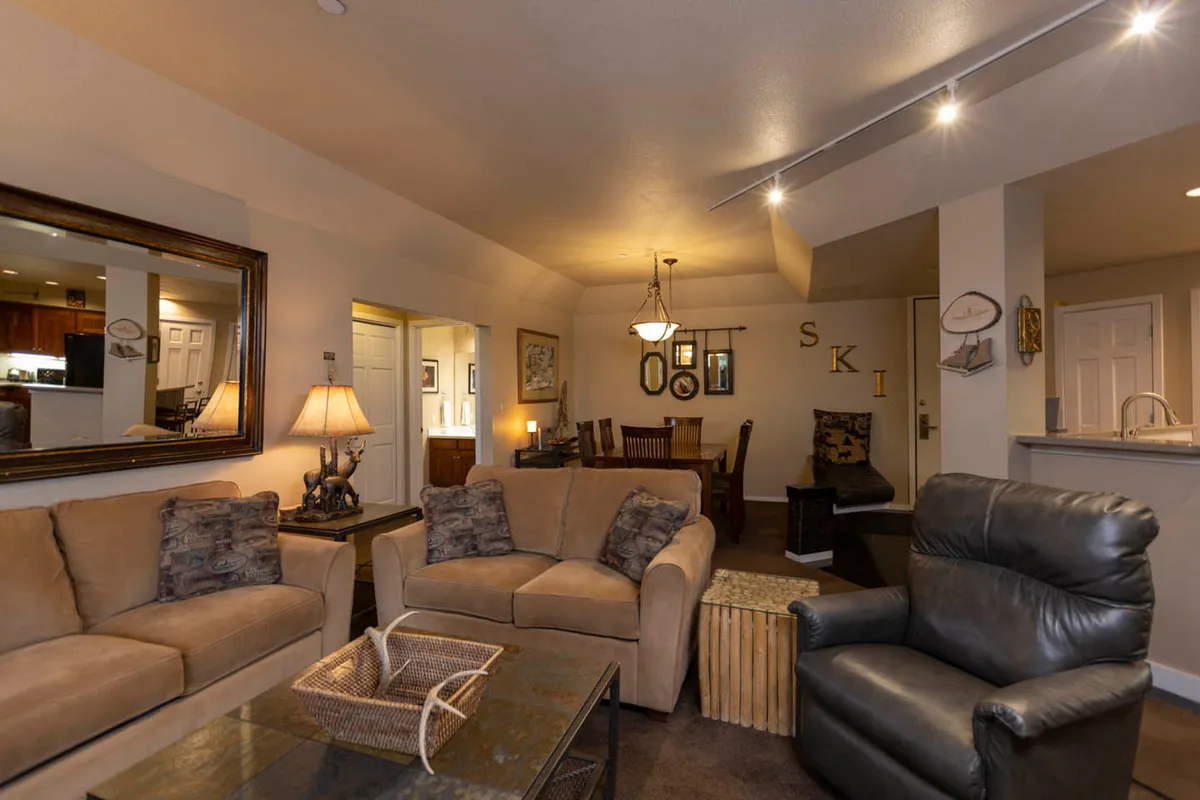 A vibrant, open-plan space with a plush sofa, coffee table, and a seamless view into the adjacent dining area. Bright lighting and inviting decor create an atmosphere ideal for socializing, playing games, or unwinding after outdoor pursuits.