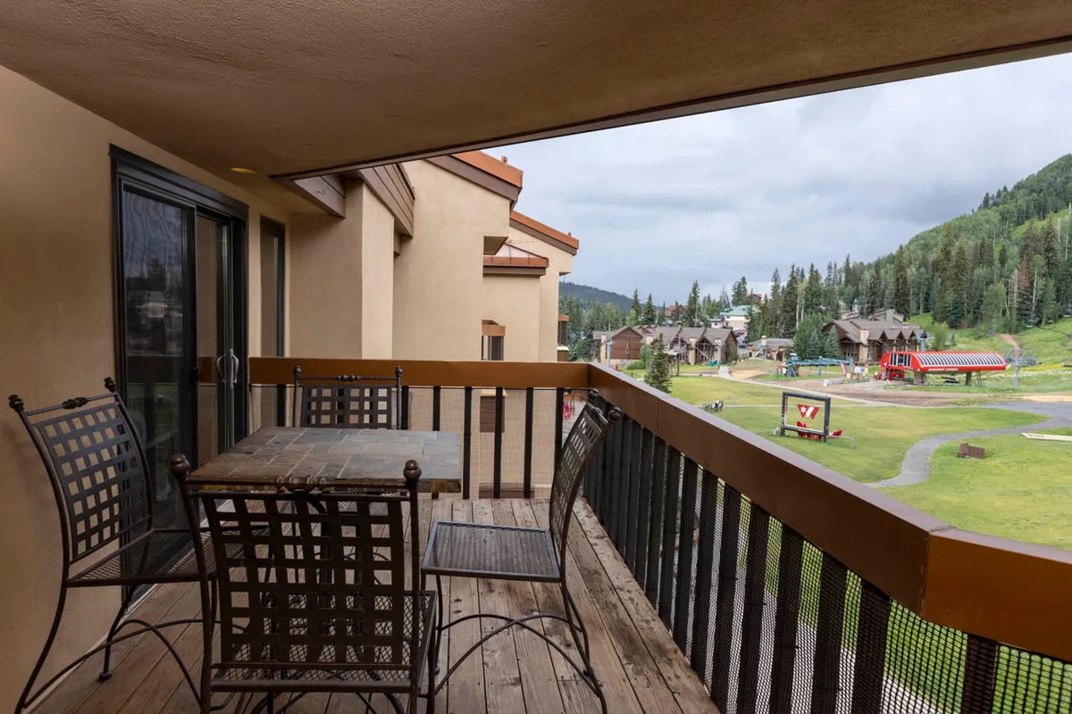 A relaxing balcony scene with comfortable furniture overlooking the landscape and neighboring buildings. The setup suggests leisurely mornings sipping coffee or gathering for meals while soaking in the scenery and fresh mountain air.